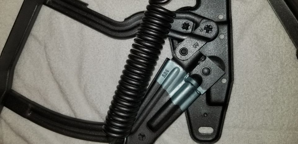 Close-up of a black spring mechanism with a silver bracket stamped "524".