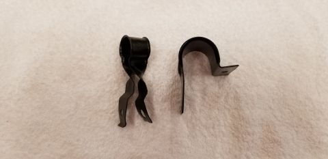 1970 Chevrolet Camaro - Two black metal clips are shown against a textured white background. The clip on the left has a twisted design with three wavy prongs, whil…