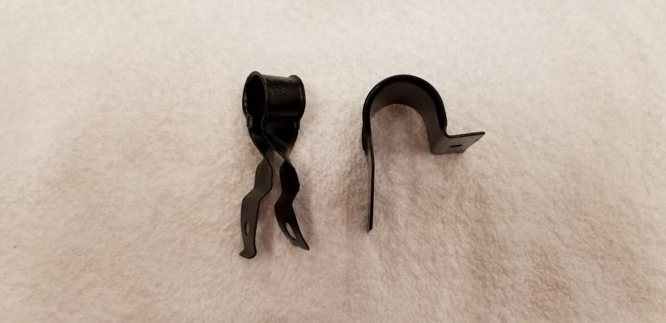 Two black metal clips, one twisted with prongs, one U-shaped with a tab.