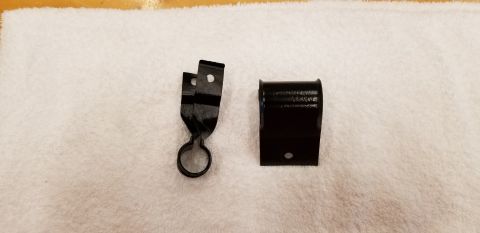 1970 Chevrolet Camaro - Two black metal automotive parts are displayed on a white towel. The part on the left is a twisted bracket with a circular clamp at the bot…