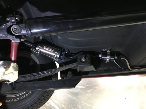 1964 Ford Fairlane - Underneath view of a vehicle's drivetrain and fuel system components, featuring a Weldon fuel pump and filter. Visible parts include the dr…
