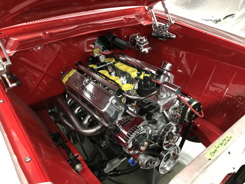 Polished Ford Racing V8 engine in a classic red vehicle's engine bay.