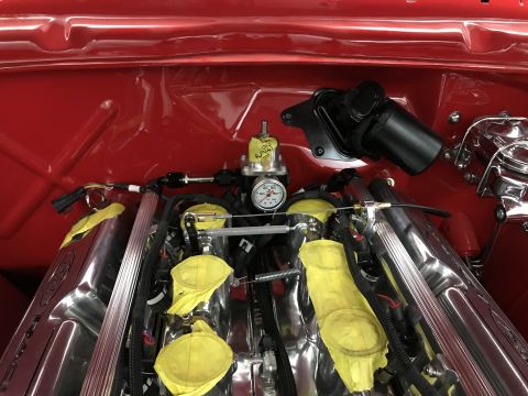 1964 Ford Fairlane - A close-up, high-angle view of a highly polished V8 engine bay in a classic car, featuring chrome intake manifolds, yellow protective cover…