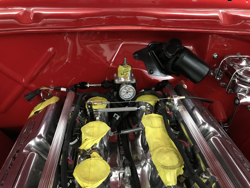 Polished V8 engine with chrome intake manifolds, yellow covers, and fuel pressure regulator.