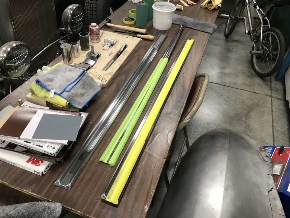 Workbench with car trim, sandpaper, and fender.