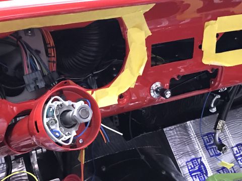 1964 Ford Fairlane - A close-up view of the red dashboard of a classic car, showing the steering column, wiring, and a toggle switch. Yellow masking tape is app…