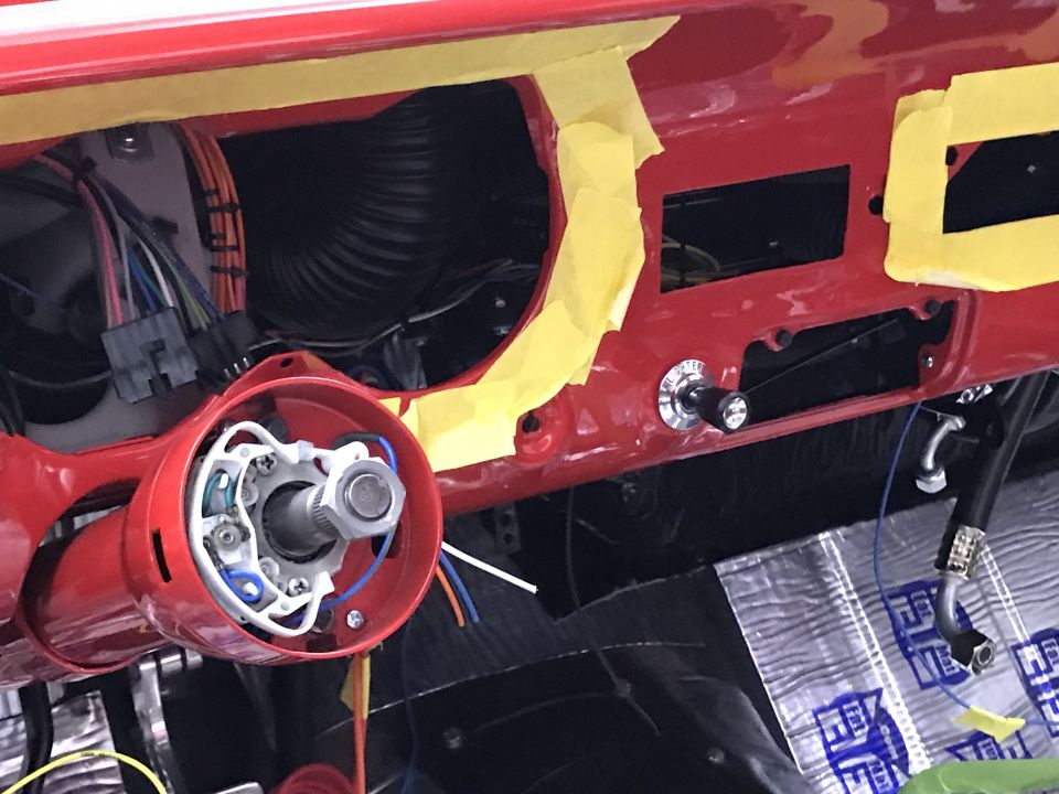 Classic car dashboard with red paint, steering column, wiring, and a toggle switch.
