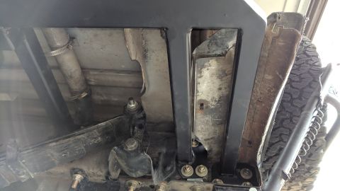 1995 Ford Bronco - Underside view of a vehicle's frame and suspension system, showing a leaf spring, exhaust pipe, and a spare tire mounted externally.