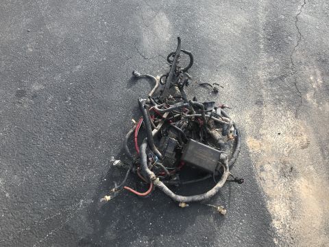 1992 Ford Bronco - A tangled pile of automotive wiring harnesses with a black fuse box is lying on an asphalt surface. The wiring appears to be from a Ford ve…