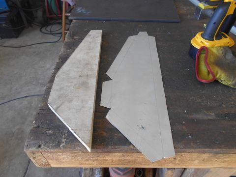 1992 Ford Bronco - Two pieces of cut material, one appearing to be wood and the other a thin sheet of metal, are laid out on a wooden workbench. A yellow and…