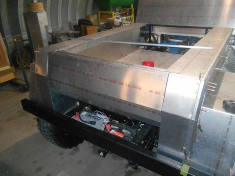 1992 Ford Bronco - A custom-built aluminum body sits atop a chassis with a visible battery and part of an engine. The vehicle appears to be in a workshop sett…