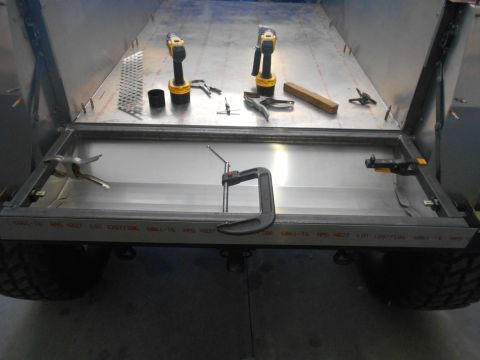 1992 Ford Bronco - A partially assembled metal bed or cargo area is shown with tools including drills and clamps. The frame of the bed is clamped in place, re…