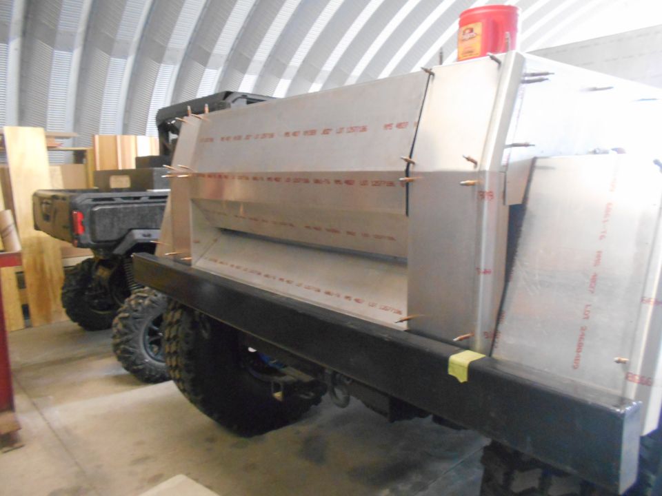 Custom truck bed modification with visible text on panels. Another vehicle is parked behind