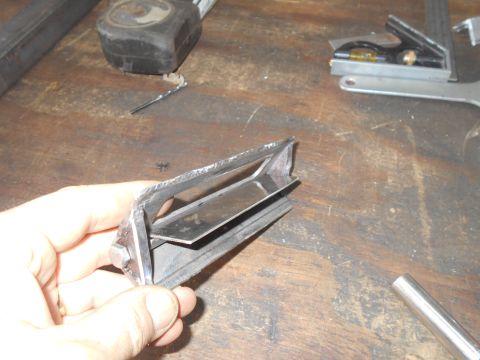 1992 Ford Bronco - A damaged chrome car vent is held in a hand over a workbench with tools.