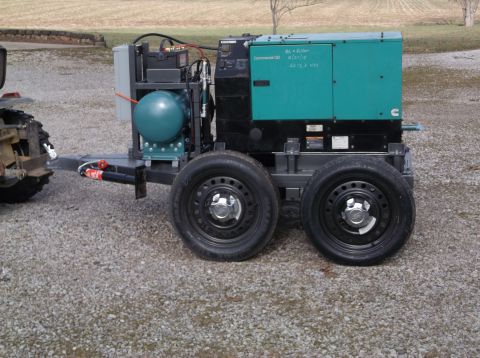 1984 Honda ATC 250 R - A portable generator unit is hitched to a tractor and parked on a gravel surface.