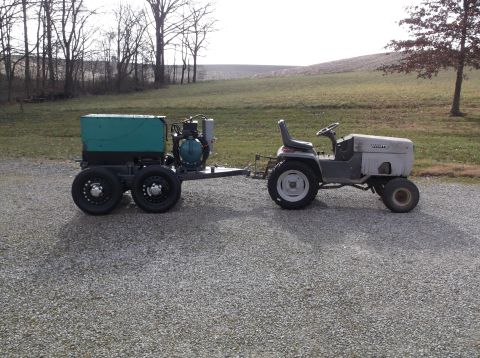 1984 Honda ATC 250 R - A tractor tows a generator on a trailer across a gravel driveway with a field in the background.