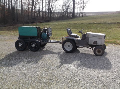 1984 Honda ATC 250 R - A White tractor tows a generator on a trailer across a gravel driveway.