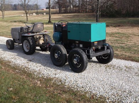 1984 Honda ATC 250 R - A portable generator is towed by a small tractor on a gravel driveway.
