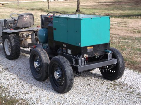 1984 Honda ATC 250 R - A generator unit is towed by a tractor, both resting on a gravel surface outdoors.