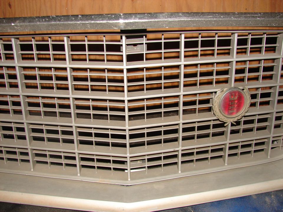 Grille with red oval emblem, light gray, close-up front view