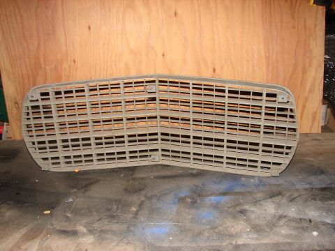 1973 Ford Ranchero - A vehicle grille is shown against a wooden background, resting on a dark surface.