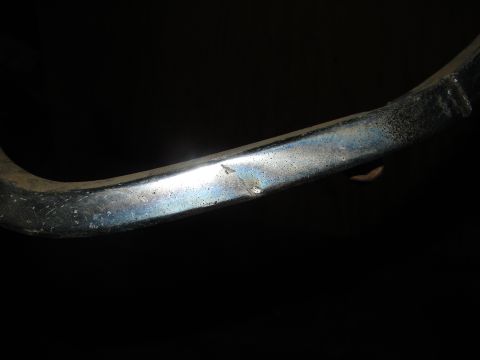 1973 Ford Ranchero - A close-up view of a chrome trim piece, showing a small dent and some discoloration against a dark background.