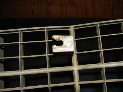1973 Ford Ranchero - A close-up view of a damaged plastic clip on a vehicle's grille, showing wear and tear.
