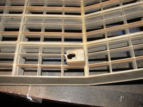 1973 Ford Ranchero - A close-up view of a damaged white plastic grille, showing a broken mounting tab.