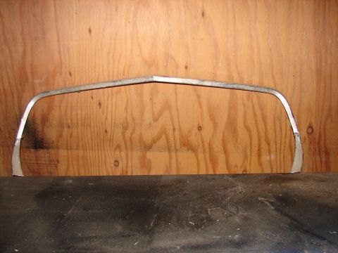 1973 Ford Ranchero - A single chrome trim piece is presented against a wooden surface, likely a car part.
