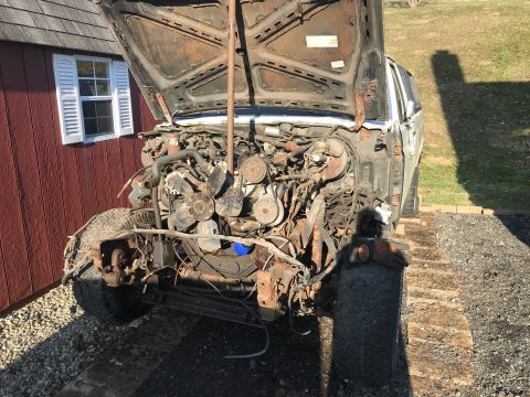 1992 Ford Bronco - Vehicle engine bay with hood open, showing disassembled engine components and front wheel.