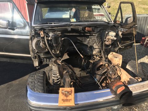 1992 Ford Bronco - The front end of a truck is dismantled, revealing the engine bay and suspension system.