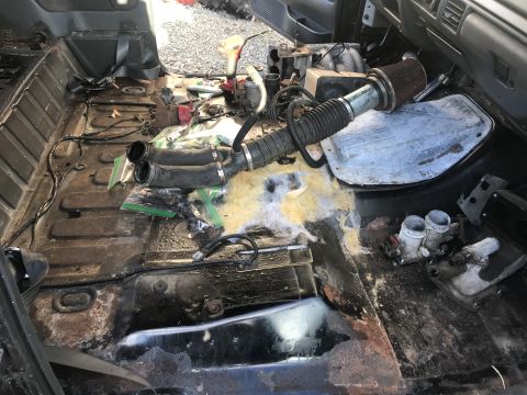 1992 Ford Bronco - The interior of a 1992 Ford Bronco is shown stripped down, with various parts and insulation removed, revealing the vehicle's floor.
