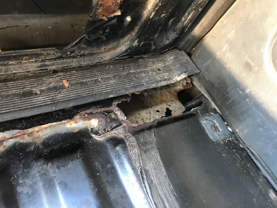 Close-up of rusted metal and black trim inside a vehicle
