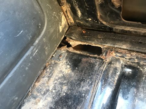 1992 Ford Bronco - The interior floor panel shows extensive rust damage and holes, indicating poor condition.