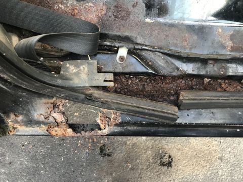 1992 Ford Bronco - Severe rust damage is visible on the floor pan and near the seatbelt anchor point.
