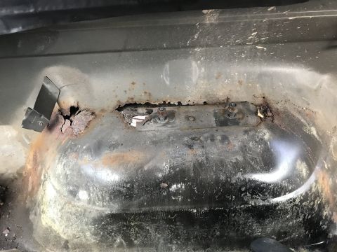 1992 Ford Bronco - Close-up of a heavily rusted vehicle floor pan, showing significant corrosion and damage.
