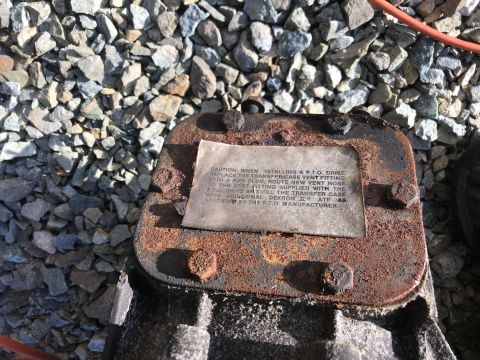 1992 Ford Bronco - A rusty transfer case part features a caution label detailing installation procedures and fluid requirements for a PTO drive.