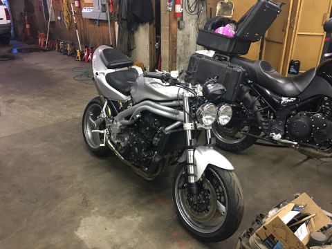 2000 Ford E350 - A silver motorcycle is parked in a garage, with another motorcycle behind it.