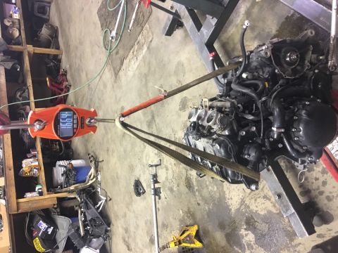 2000 Ford E350 - An engine is suspended by straps and a hoist scale in a workshop setting.