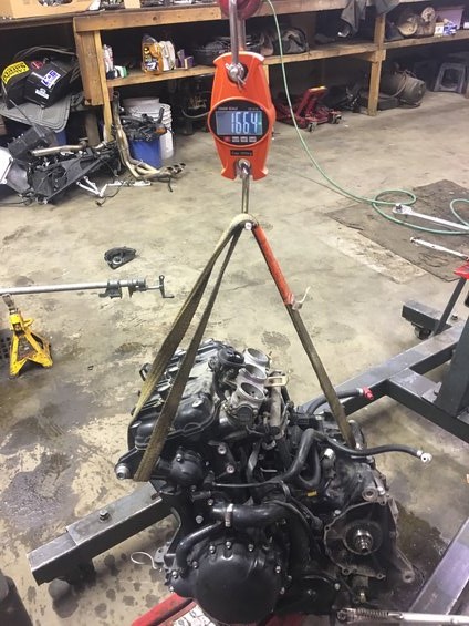 2000 Ford E350 - An engine is suspended by straps from a digital scale in a workshop setting.