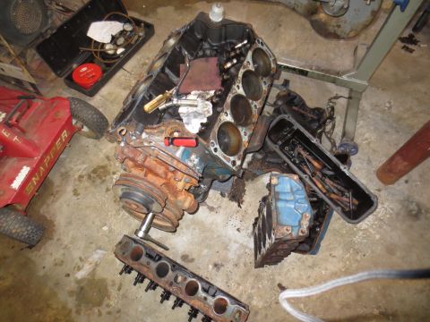 1967 Ford F-250 - Engine parts laid out on the floor, including a block, heads, and pan, with a lawnmower nearby.