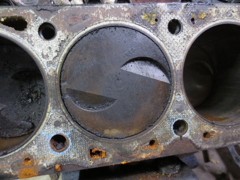 Close-up of a dirty engine cylinder with a piston inside. Shows rust and wear