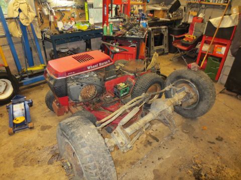 1967 Ford F-250 - A red Wheel Horse riding mower is disassembled in a garage, with its rear axle detached.