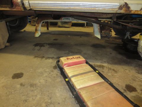 1967 Ford F-250 - Vehicle underbody with a creeper in a workshop setting.