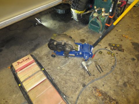 1967 Ford F-250 - A transfer case is being worked on in a garage, with tools and a creeper nearby.