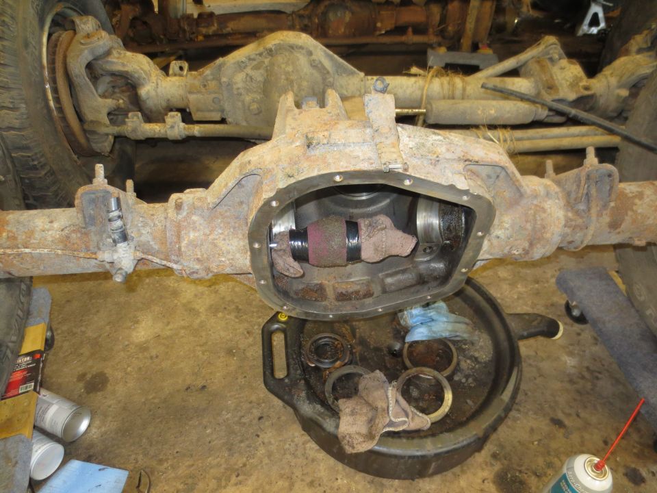 Rear differential with cover removed, showing internal components and a drain pan with parts