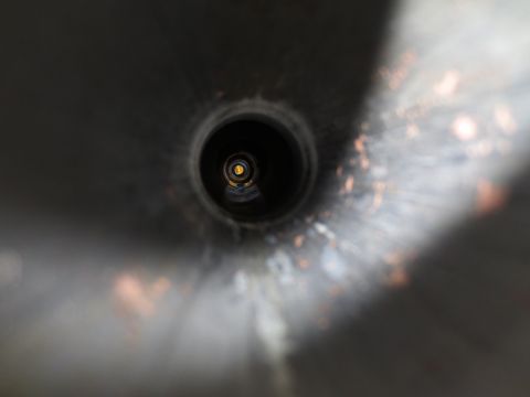 1967 Ford F-250 - A view into the end of a vehicle's exhaust pipe, showing a dark, circular opening with some metallic reflections.
