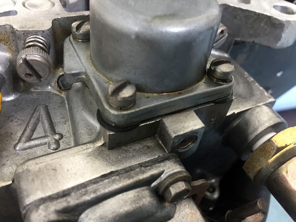Carburetor part with a cast number 4 and visible screws and gaskets
