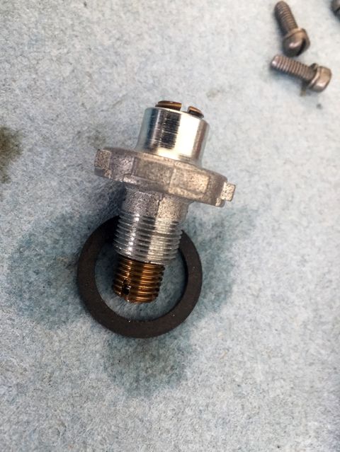 1978 Ford Bronco - Close-up of a fuel pressure regulator, gasket, and screws, likely for automotive repair.