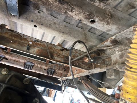 1978 Ford Bronco - The undercarriage of a heavily rusted vehicle shows leaf springs and brake lines, with no clear year identification.